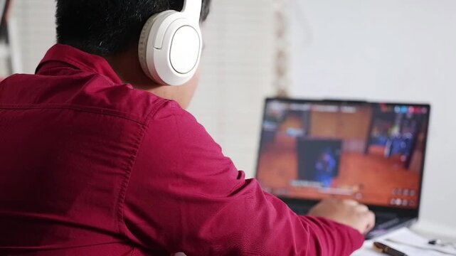 Play online games. Cheerful gamer man wearing headphones playing video game on computer,expressing satisfaction and joy.E-sport championship tournament, cyber sport team.Multiplayer online competition