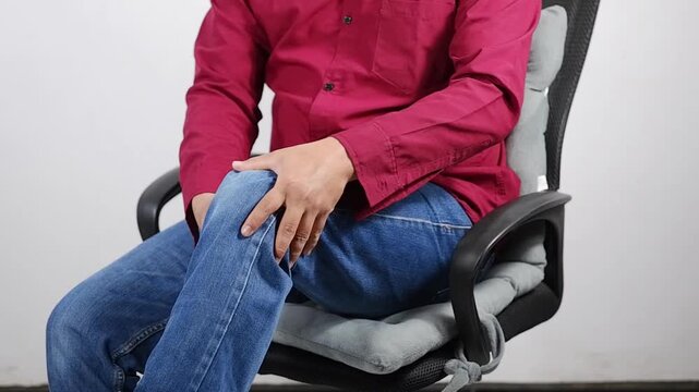 Knee pain, arthritis, joint inflammation, and degenerative changes. A man suffering from leg pain performs a self-massage at home. It focuses on joint care, relaxation, and alleviating knee pain or of