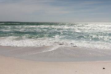 Obraz premium Waves crashing on shore at beach against sky during sunny day