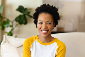 Portrait of african american young woman smiling sitting on the couch at home