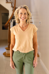 Portrait of caucasian senior woman smiling while standing in the living room at home