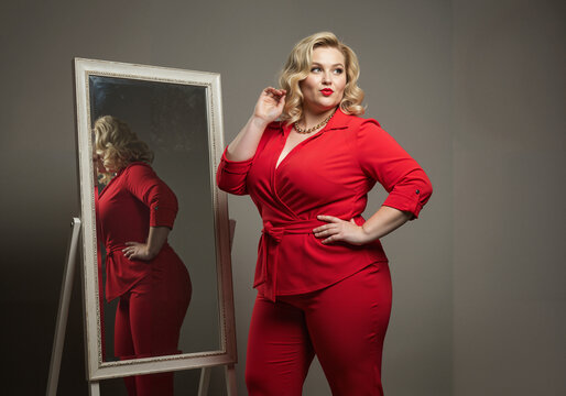 Confident woman posing in red outfit with reflection in mirror  