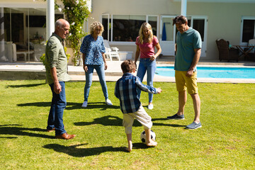 Caucasian three generation family playing football together in the garden