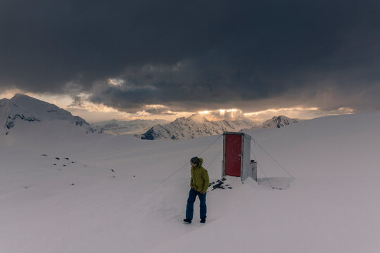 A man walks away from an outhouse in the Northern Rockies in Canada.
