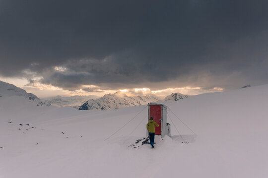 A man walks to a outhouse in the Northern Rockies of Canada.