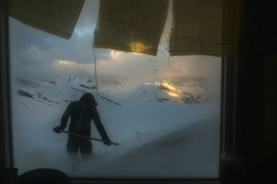 A man shovels snow outside a hut in the Northern Rockies in Canada.
