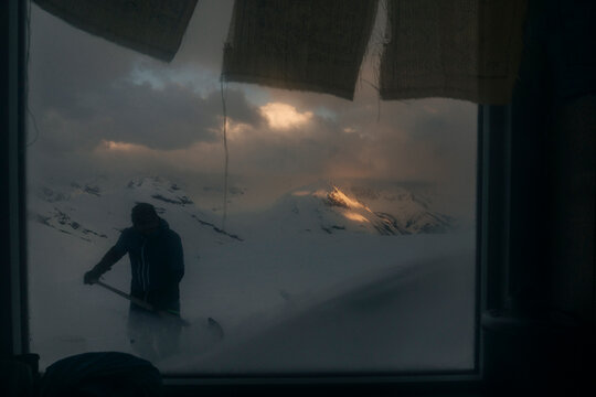 A man shovels snow outside a hut in the Northern Rockies of Canada.