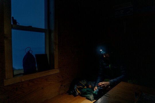 A man fixes a jacket in a backcountry hut in Canada.