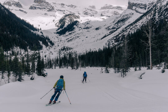Two skiers descend a valley in the Canadian backcountry.