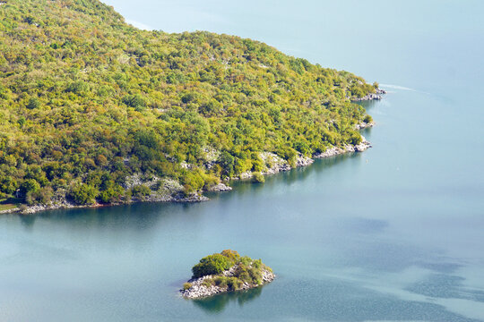Small green islands on the calm surface of Slano Lake in Montenegro. Represents untouched nature, freshwater ecosystems, sustainable tourism, Balkan biodiversity, and peaceful wilderness landscapes.