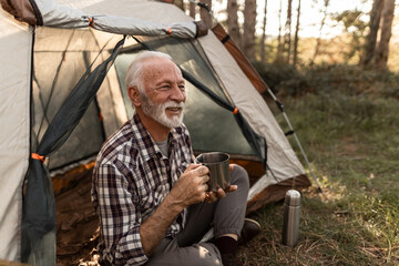 Senior man enjoying coffee while camping outdoors