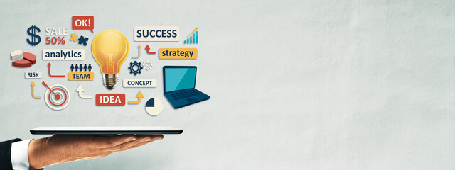 Business strategy concept with light bulb, laptop, and digital analytics symbols floating above hand holding tablet on soft textured background.