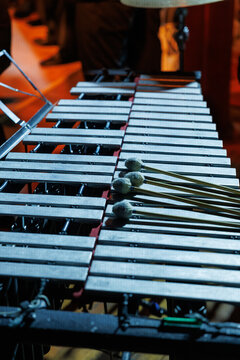 A vibraphone rests on stage under warm lights, mallets placed across metal bars, awaiting a live performance in an orchestral concert setting