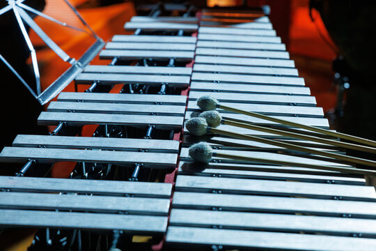 A vibraphone rests on stage under warm lights, mallets placed across metal bars, awaiting a live performance in an orchestral concert setting