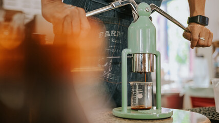Barista's hands extracting fresh espresso using a manual lever machine.