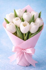 Elegant white tulip bouquet wrapped in pink paper with a matching ribbon bow.