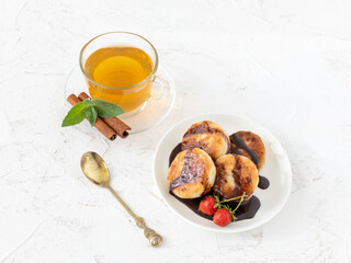Curd fritters on the porcelain plate with a cup of tea.