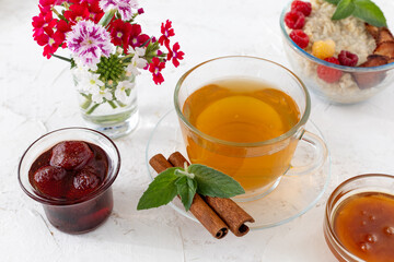 Glass cup of green tea with cinnamon and leaves of mint on a saucer.