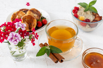 Glass cup of green tea with cinnamon and leaves of mint on a saucer.
