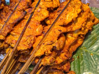 A high-angle, close-up view of traditional Thai-style grilled chicken (Gai Yang) displayed at a street food market.
