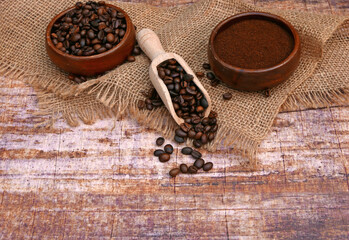 Coffee beans and coffee powder with a scoop on a wooden background with space for text.