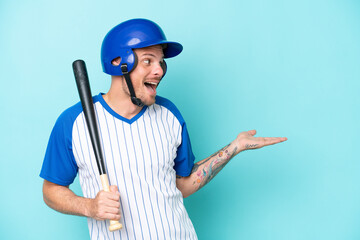 Baseball player with helmet and bat isolated on blue background with surprise expression while...
