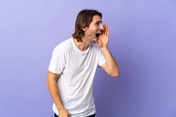 Young handsome man isolated on purple background shouting with mouth wide open to the side