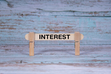 Fototapeta premium Interest symbol. Single Wooden stick squeezed by Clothespins, Grungy blue Wooden Texture Background. Business and Interest concept with copy space