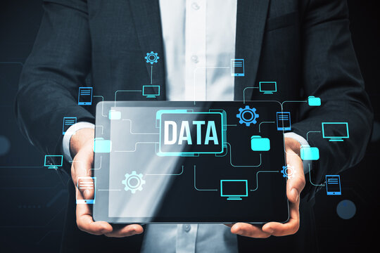 Businessman holding tablet with digital data interface and cloud technology connections on dark background representing online network system. - Powered by Adobe