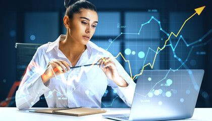 Businesswoman analyzing upward financial trends on laptop at night in office with digital graph overlay and arrow growth concept.