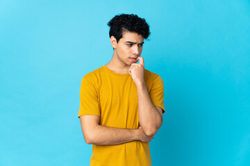 Young Venezuelan man isolated on blue background nervous and scared