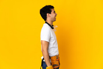 Venezuelan electrician man isolated on yellow background laughing in lateral position