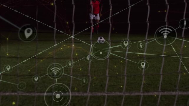 Animation of network of digital icons over mid section of male soccer player taking a penalty kick