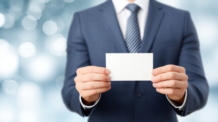 In a sleek, contemporary office, a well-dressed man stands confidently, presenting a blank business card with both hands. Soft light creates a calm atmosphere