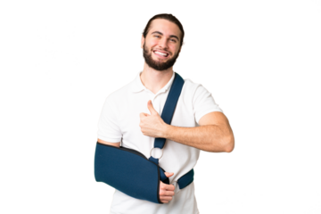 Young handsome man with broken arm and wearing a sling over isolated chroma key background giving a thumbs up gesture
