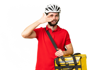 Young delivery man with thermal backpack over isolated chroma key background covering eyes by hands and smiling