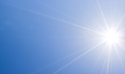 A photograph of the sun shining brightly against a beautiful natural backdrop of a blue sky.