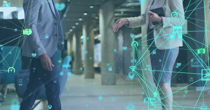 Animation of connected icons forming globes over diverse businesspeople shaking hands in office