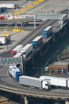 HIGH ANGLE VIEW, CLOSE UP: Cargo trucks driving in a line through port terminal