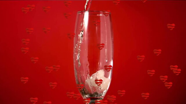 Droplet falling into champagne flute initiating pouring, rising foam and drifting heart overlays