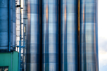 Close-up of large, cylindrical metal silos. They are used in industrial plants to store large quantities of free-flowing bulk materials.
