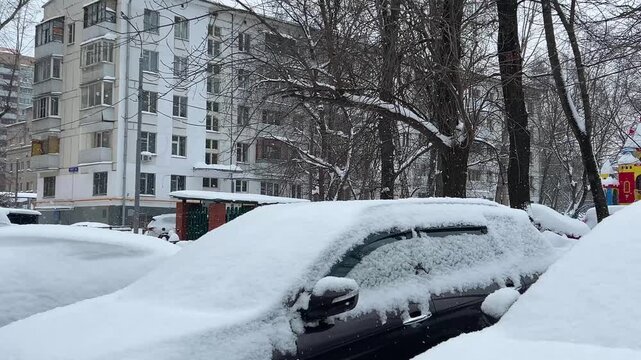 Parked cars at the street after huge snowfall in Moscow, Russia. Automobiles covered with snow. Winter concept.