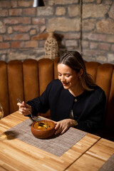 Woman enjoys a meal at a restaurant with a cozy atmosphere