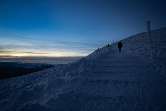 Frozen hiking trail from Wołosate to Tarnica in the Bieszczady Mountains, photographed before sunrise during blue hour. Snow-covered path, icy landscape and dramatic pre-dawn sky create a cold, peacef