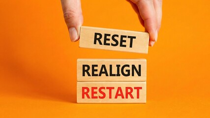 Reset Realign Restart symbol. Concept words Reset Realign Restart on wooden blocks. Businessman hand. Beautiful orange background. Business and Reset Realign Restart concept.