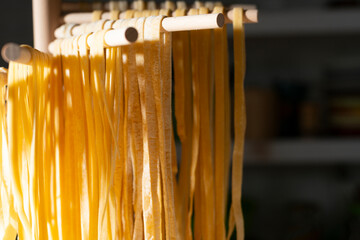 Homemade noodles hanging on wooden dryer rack closeup low angle view