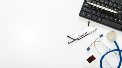 Doctors desk flat lay background of stethoscope pulse oximeter laptop glasses and pen on table with copy-space