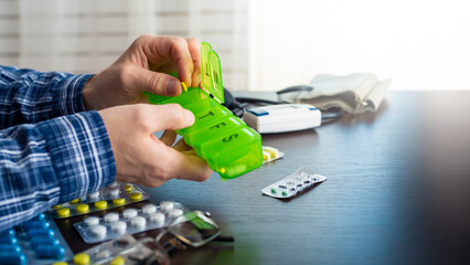 Middle aged caucasian man distributing scheduled dose of medication in dosette box