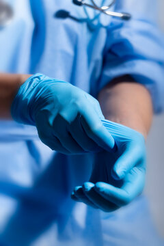 Healthcare professional putting on blue medical gloves on white background with copy space