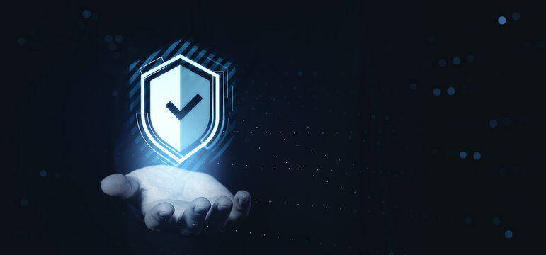 Cybersecurity shield hologram in hand representing data protection and safety concept on futuristic dark digital background with glowing elements. - Powered by Adobe
